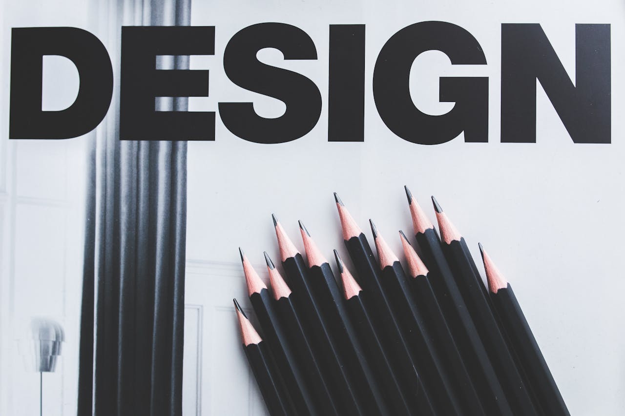 Black pencils arranged creatively next to large typography DESIGN.